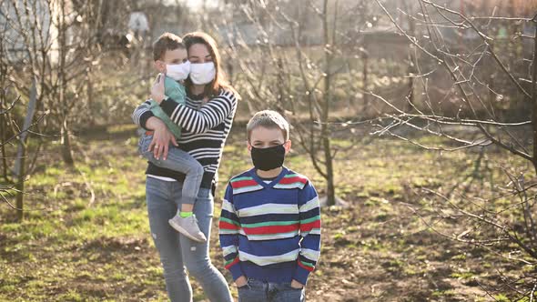 Caring Mother Hugs the Masked Child, and the Second Child Is in Front