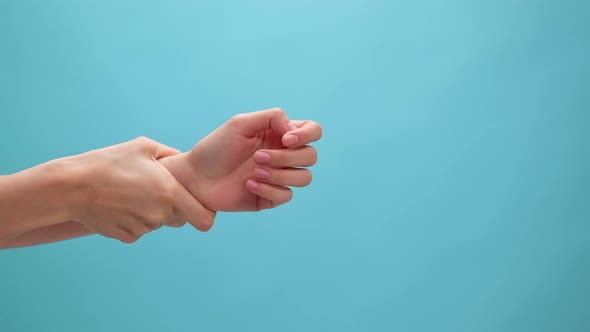 Close up shot of woman hand touching wrist and stretch joint on the blue background alt
