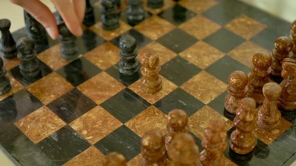 A brown and black stone chess set in the early stage of the match with pawns beinged into the center alt