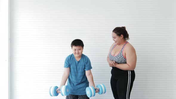 Asian family mother training with son fat exercise with dumbbell at home alt