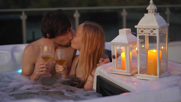 A Young Man and Woman are Relaxing in the Hot Tub on a Rooftop with a View on Mountains During alt