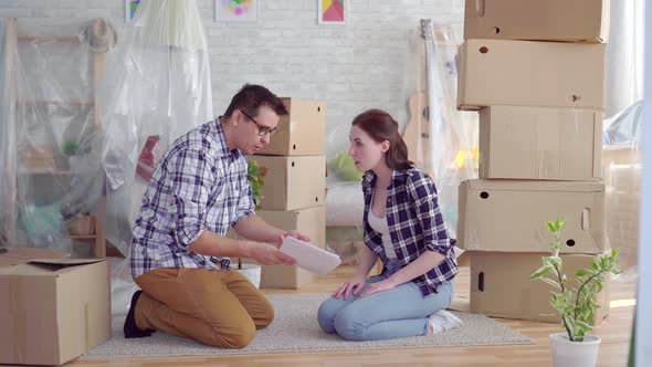 Tired and Frustrated Couple Middleaged Man and Woman Arguing in the Middle of Moving Boxes alt