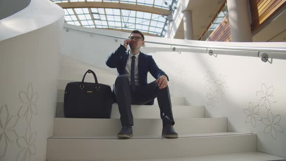 Successful Confident Businessman Sitting on Stairs Talking on Cell Mobile Phone alt