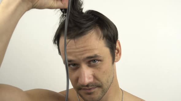 A Young Funny Guy Cuts His Hair Using a Hair Clipper While Sitting at Home in Quarantine