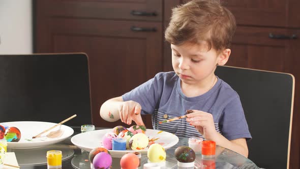 Easter Celebration Concept. Happy Little Boy Decorating Easter Eggs for Holiday. alt