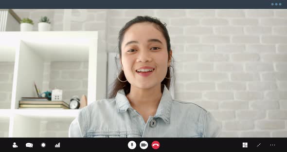 Young Asian girl smiling, waving hand and talking on video call at home