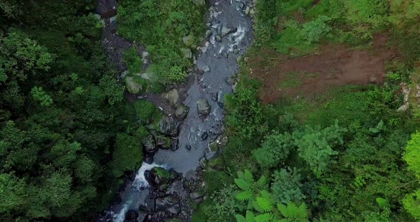 Aerial flyover river stream floating between rocks in jungle of Indonesia during daytime - Kedung Ka alt