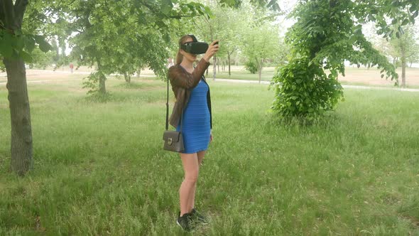 Beautiful Girl In A Virtual Reality Helmet Uses A Virtual App In The Park