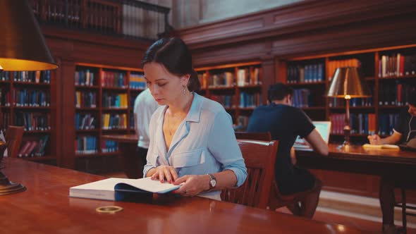 Young woman reading a book in the library of New York City alt