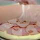 Cook Places Bacon and Smoked Sausage on Raw Pizza