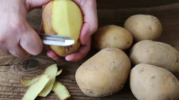 Hands peeling potato on rustic wooden table