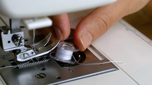 Woman hands with gray fabric sewing with a sewing machine. Women's hands sew on a sewing machine. alt