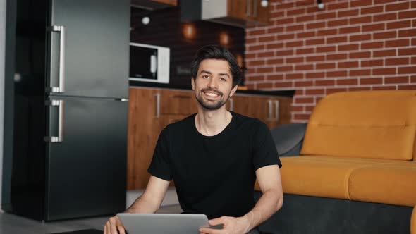 Man Sitting on the Mat on the Floor with Laptop at Home in Living Room alt