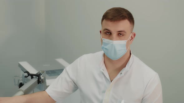 Portrait of a Young Therapist Doctor in a Medical Mask Standing in a Hospital Corridor and Looking alt