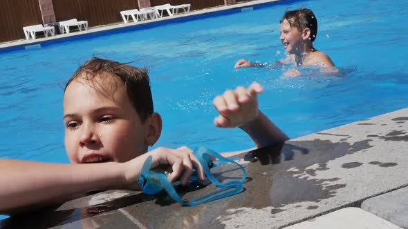 Two Teenagers are Swimming in a Beautiful Blue Pool Using Water Goggles and a Ball alt