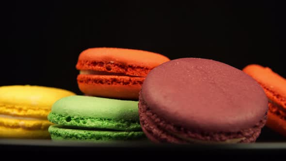 A Colorful Macaroons are rotating on a black dish