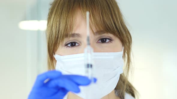 Close Up of Female Doctor in Mask Preparing Injection for Patient alt