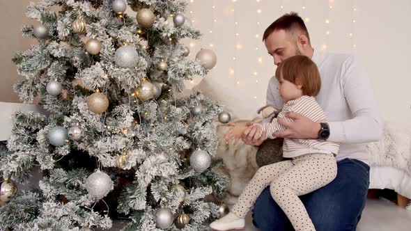 Child with Dad Decorates Christmas Tree with Balls on the Background of Bright Festive Lights alt