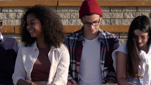 Resting with Friends. Five Smiling Groupmates Sitting Together After Classes Outside the University alt