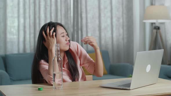 Smiling Asian Woman Drinking Vodka During Having Video Call On A Laptop At The Home alt