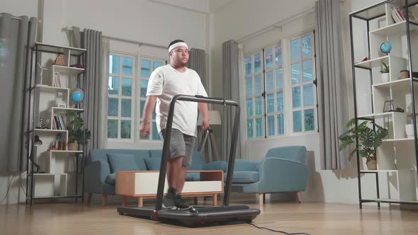 Asian Fat Man Training On Walking Treadmill At Home alt