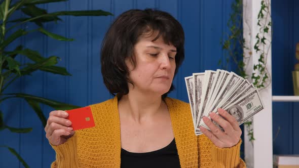 Middle Aged Woman is Holding Credit Card and Money and Choose Credit Card
