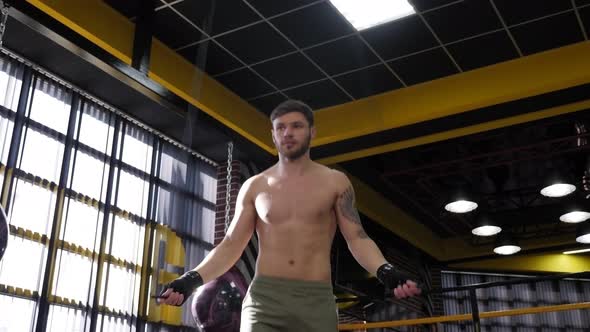A Handsome Male Boxer Jumps on a Skipping Rope in a Boxing Gym alt