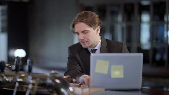 Focused Caucasian Man Checking Email Closing Laptop As African American Colleague Bringing Beer alt