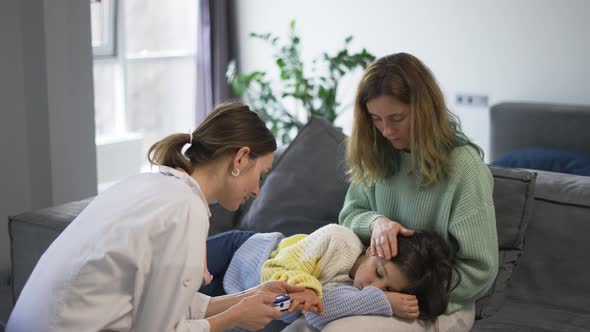 Doctor Examines Little Girl Checks Oxygen Level on Mom's Knees alt