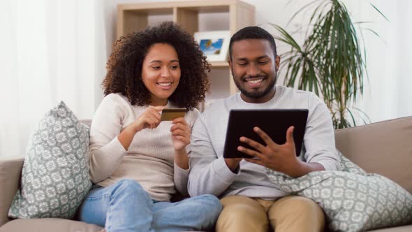 Couple with Tablet Pc and Credit Card at Home alt