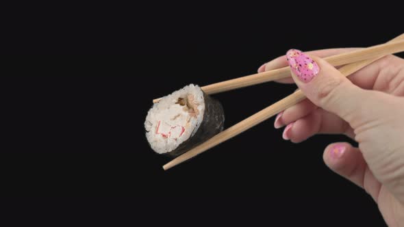 Female Hands Hold Japanese Chopsticks with Sushi Rolls on Transparent Background alt