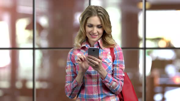 Young Blond Casual Girl Texting To Someone on Her Smartphone alt