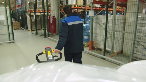 Back View of Forklift Operator in Special Uniform Pulling the Batch of Packaged Containers of