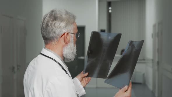 Senior Doctor Smiling To the Camera While Examining X-ray Scans