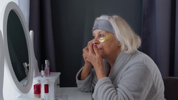 Old Senior Elderly Woman Grandmother Applying Anti-wrinkle Eye Patch, Putting Makeup on at Home alt