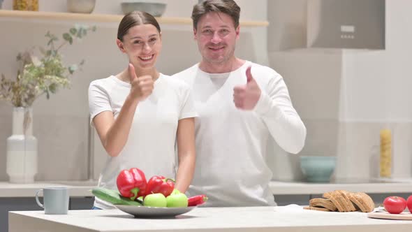 Mixed Race Couple Showing Thumbs Up Sign in Kitchen alt