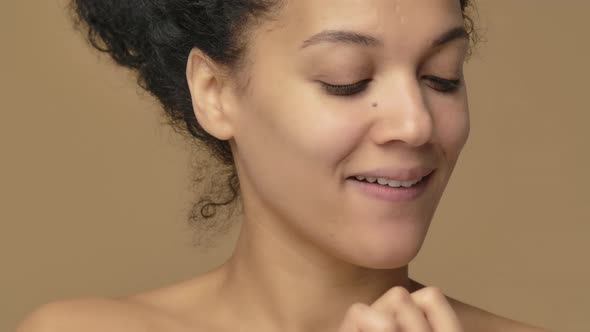 Beauty Portrait of Young African American Woman Smears Face Care Cream on Tip of Her Nose and Smiles alt