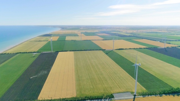 Group of windmills for electric power production in the agricultural fields. Aerial view