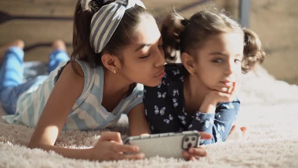 Two Middle Eastern Young Girls on the Bed with a Smartphone