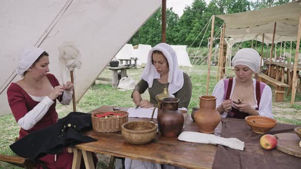 Group of People Dressed in Medieval Clothes Spending Time Together During Sitting at the Table. alt