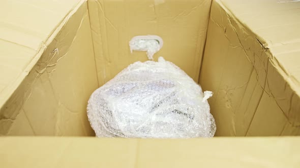 Closeup View of a Caucasian Man Packing Wrapped in Plastic Good
