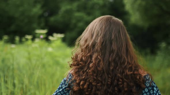 Cheerful Girl with Beautiful Long Curly Hair Runs and Looks at the Camera Back View Slow Motion