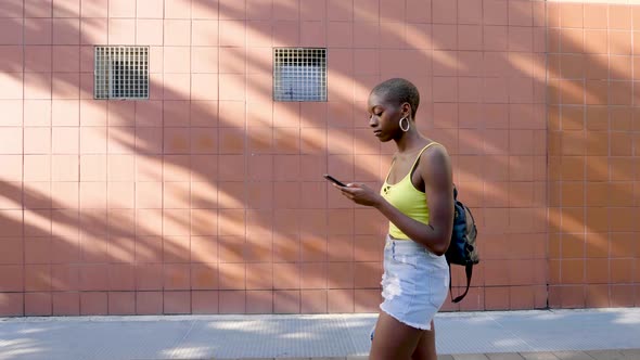 Slow motion shot of young woman using smartphone in city alt