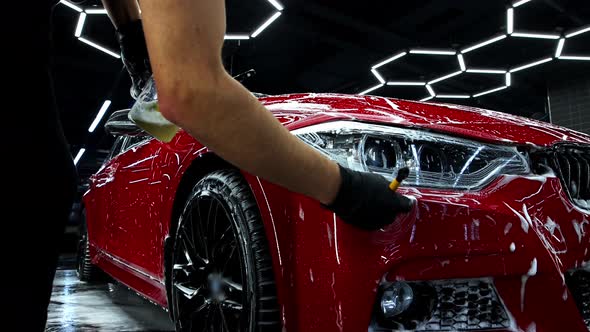Autodeiling  a Man Washes the Headlights of a Car Rubbing Them with a Brush alt