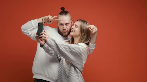 Happy Couple Woman Man Doing Selfie Together Using Smartphone on Red Background