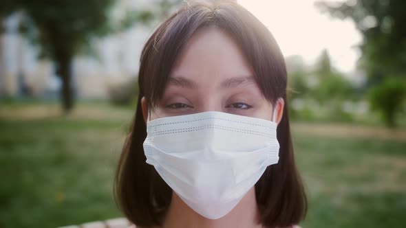 Portrait of Nicelooking Asian Multirace Young Woman in Medical Mask Looking Into Camera and Smiling alt