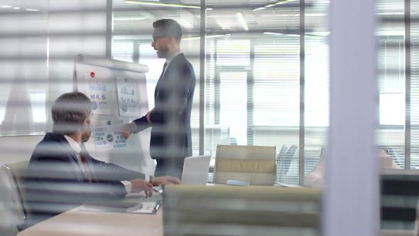 Businessman Delivering Financial Presentation in Conference Room alt