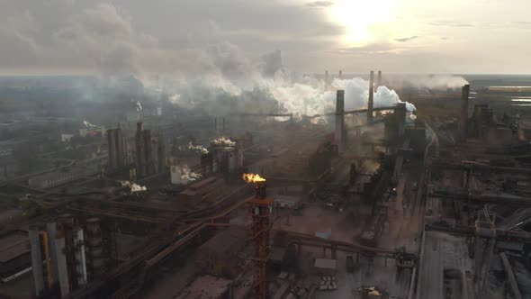 Steel Factory Pipes During Sunrise Time. High Above Metallurgical Plant and Smoke Cloud Is Coming