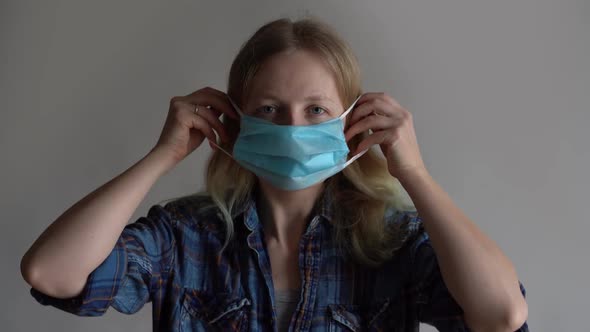 Protection Against Coronavirus. Woman Puts a Mask on Her Face.
