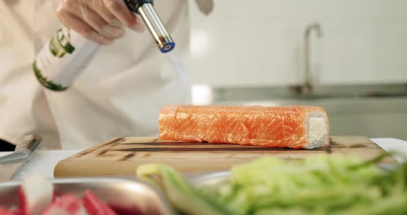 Restaurant Kitchen. Male Sushi Chef Prepares Japanese Sushi Rolls of Rice, Salmon, Avocado and Nori alt